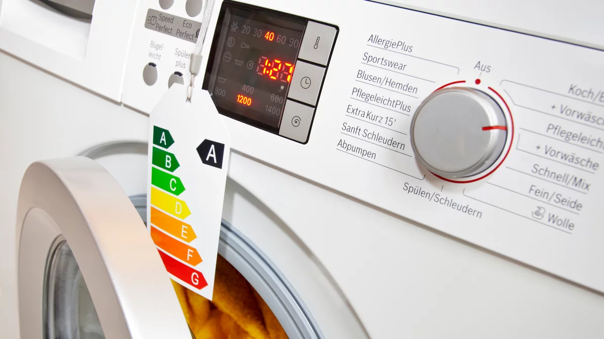 Halbschräger Blick auf Bedienfeld einer Waschmaschine der Energieeffizienzklasse A mit halb geöffneter Tür und eingeschalteter Digitalanzeige.