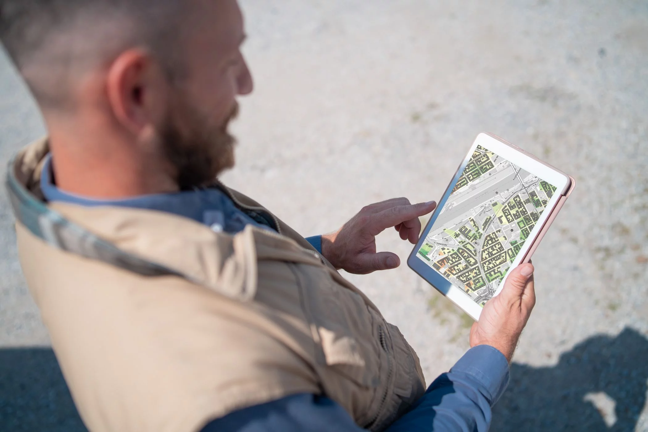 Mann mit Tablet auf dem eine Stadtkarte abgebildet ist